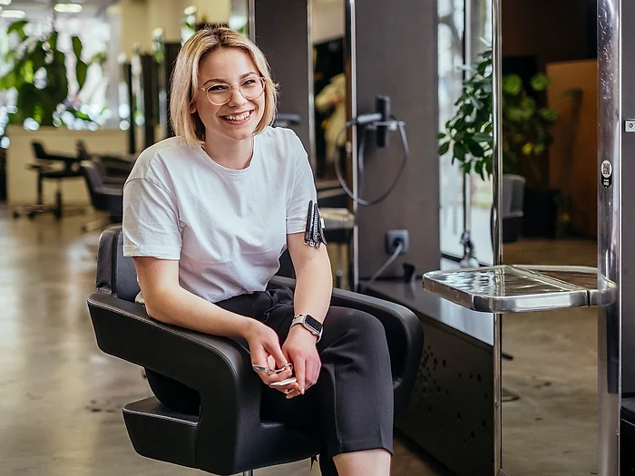 A smiling salon owner sitting in her styling chair