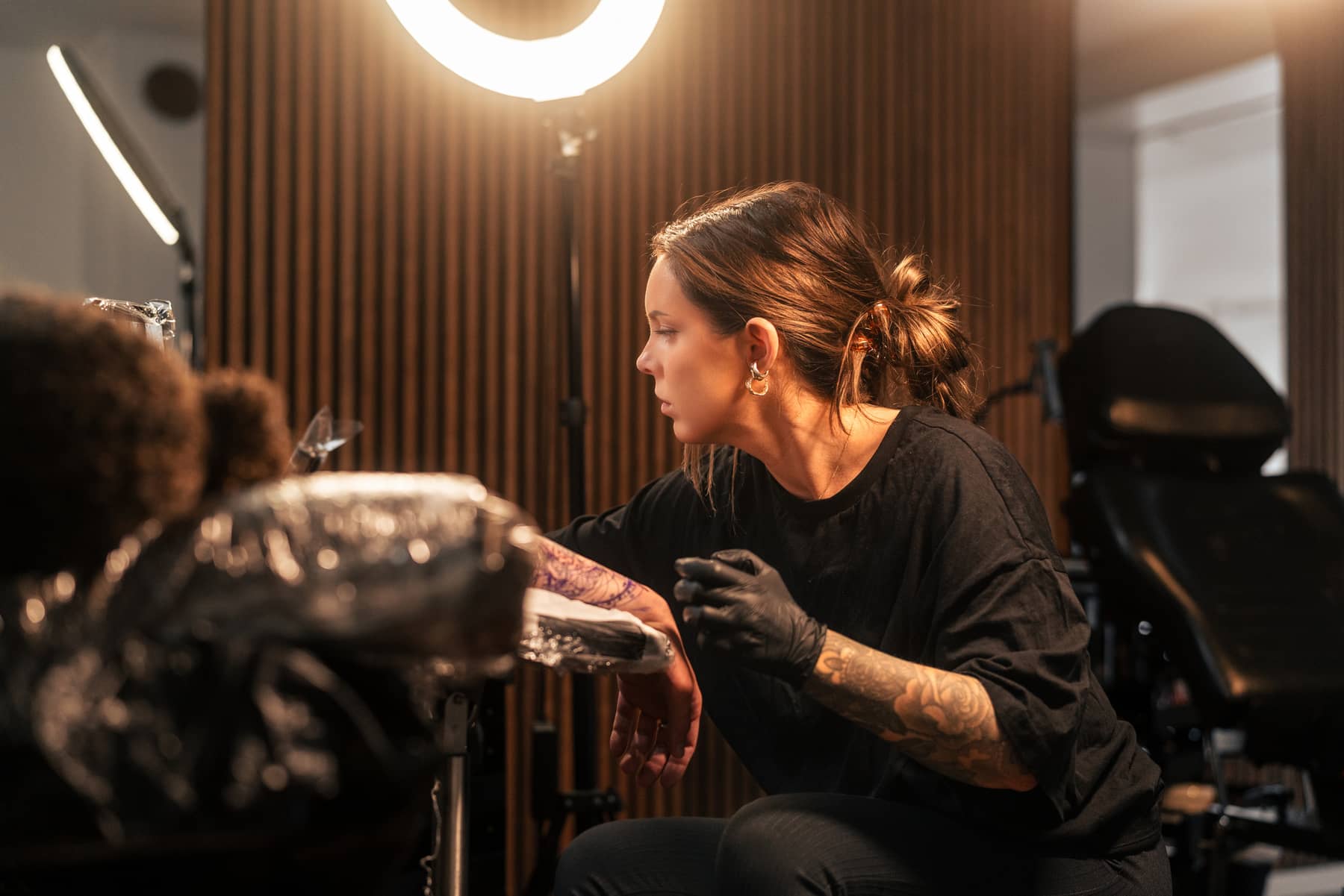 Tattoo artist inking a detailed forearm tattoo on a client at a tattoo studio.